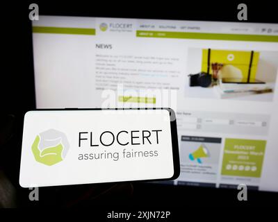 Stuttgart, 25.03.2023: Person mit Mobiltelefon mit Logo der Produktzertifizierungsstelle FLOCERT GmbH auf dem Bildschirm vor der Webseite. Stockfoto