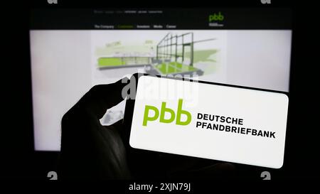 Stuttgart, Deutschland, 04.01.2023: Person mit Mobiltelefon mit Logo der Deutschen Pfandbriefbank AG (PBB) auf dem Bildschirm vor dem Geschäft Stockfoto