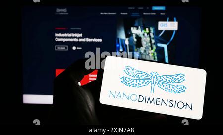 Stuttgart, Deutschland, 04.01.2023: Person, die ein Mobiltelefon mit dem Logo der Firma Nano Dimension Technologies Ltd. Auf dem Bildschirm vor der Geschäftsstelle hält Stockfoto