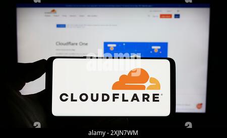 Stuttgart, Deutschland, 17.06.2023: Person, die ein Mobiltelefon mit dem Logo des US-amerikanischen IKT-Unternehmens Cloudflare Inc. Auf dem Bildschirm vor der Website des Unternehmens hält. Konzentrieren Sie sich auf Stockfoto