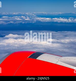 Triebwerk eines Verkehrsflugzeugs, das über einem Wolkenmeer über dem Meereswasser auf den Kanarischen Inseln fliegt. Stockfoto