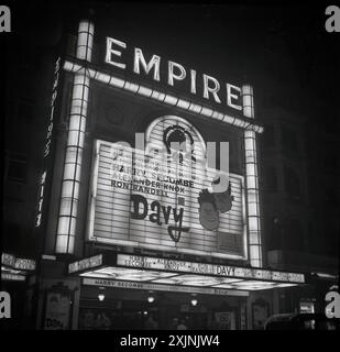 1960er Jahre, historischer Blick auf das Empire Cinema, Leicester Square, London, England, Großbritannien, wo der Film Davy mit Harry Secombe, der populären britischen Radio-Persönlichkeit der Epoche. Dies war eine MGM-Veröffentlichung von an Ealing Film, der letzte von den britischen Studios gedreht wurde. Es war der erste britische Film, der in Technirama gedreht wurde. Ursprünglich 1884 als Varieté-Theater erbaut, wurde das Empire 1925 von Metro-Goldwyn-Mayer erworben und zum Kino umgebaut, um Filme zu zeigen. Stockfoto