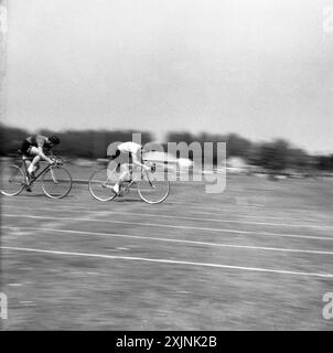 1950er Jahre, Whit Sunday Cycling, zwei männliche Radfahrer, die auf einer Grasstrecke bei einem Outdoor-Radsport-Event in England, Großbritannien, antreten. Stockfoto