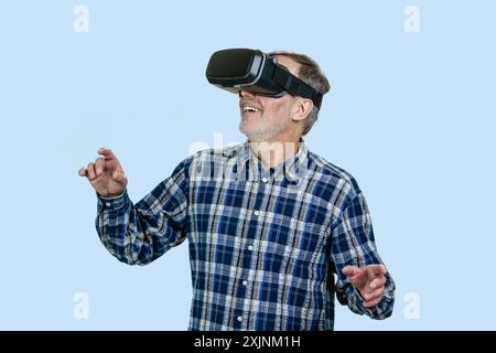 Glücklicher älterer Mann, der die virtuelle Realität im Headset erlebt. Isoliert auf Blau. Stockfoto