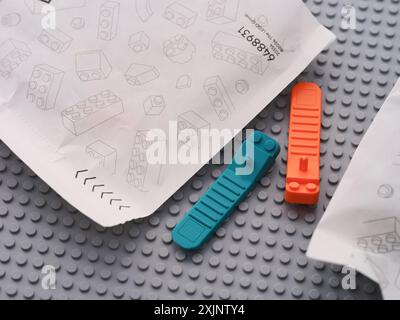 Tambow, Russische Föderation - 22. Juni 2024 Lego-Ziegeltrenner liegen zwischen Papiertüten mit Lego-Stücken auf einer grauen Grundplatte Stockfoto