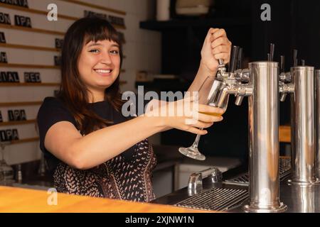 Lächelnde Barkeeperin serviert Bier vom Fass. Stockfoto