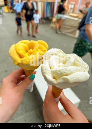 Wunderschönes und köstliches italienisches Eis in Waffelkegel vor den Straßen. Eis in den Händen auf dem Hintergrund von Gebäuden und Völkern Italiens. Reisen Stockfoto