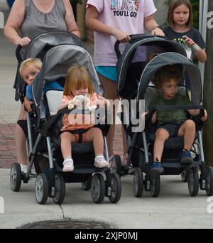 Zwei Frauen schieben Kleinkinder in einem Tandemwagen oder Doppelwagen auf einem Bürgersteig in Brevard, North Carolina. Stockfoto