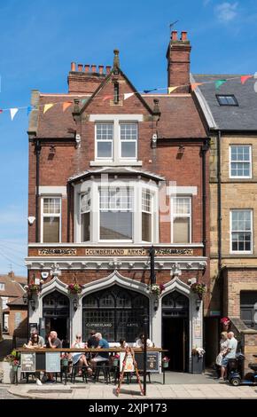 Leute sitzen vor dem Cumberland Arms Pub in Tynemouth Front Street, England, Großbritannien Stockfoto