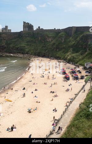 Menschen, die die Sommersonne am Strand von King Edward's Bay in Tynemouth, England, genießen Stockfoto