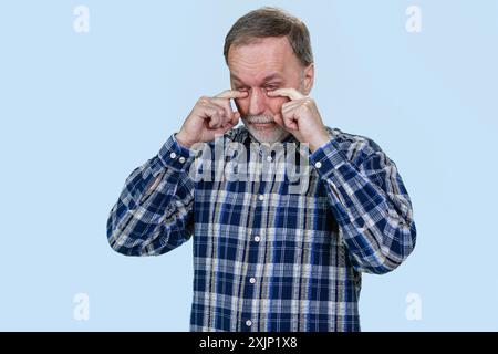 Porträt eines traurigen, schreienden älteren kaukasiers. Isoliert auf Blau. Stockfoto