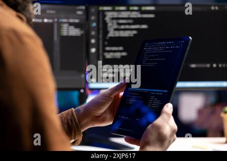 Computerwissenschaftler, der Software-Qualitätssicherung mit einem Tablet durchführt und den Quellcode vor der Implementierung liest. Entwickler prüfen die Codierung auf tragbaren Geräten, um potenzielle Probleme zu beheben Stockfoto
