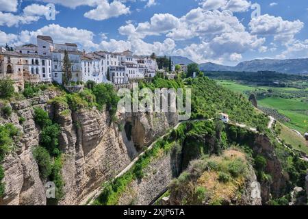 Ein Blick auf die Gebäude am Rande einer spektakulären Klippe mit einem Wanderweg mit Blick auf ein Tal und Berge. Stockfoto