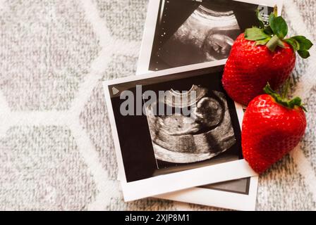 Foto des Fetus auf Ultraschall und Erdbeere. Infertilitätsbehandlung. Die künstliche Besamung. Ein Baby mit IVF bekommen. Sonographische Ergebnisse der Schwangerschaft Stockfoto