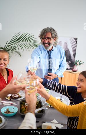 Lächelnde kaukasische glückliche Familie beim Essen zusammen mit Weißwein am Tisch drinnen. Stockfoto