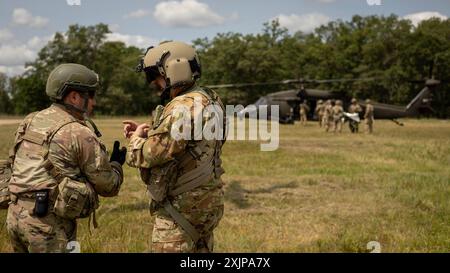 Ein Kampfmediziner des 224. Brigade Ingenieur-Bataillons, 2. Brigade Combat Team, 34. Infanterie-Division, Iowa Army National Guard, koordiniert die medizinische Evakuierung eines Soldaten mit simulierten Verletzungen mit einem UH-60 Black Hawk Hubschrauberbesatzungsmitglied aus Kompanie G, 1. Bataillon, 189. Fliegerregiment, Oregon Army National Guard, während einer Massenübung im Rahmen einer XCTC-Rotation (Exportable Combat Training Capability) am 18. Juli 2024 in Camp Ripley, Minn. Während der XCTC trafen Komponenten des 2/34. BCT (einschließlich Infanterie, Kavallerie, Feldartillerie und Ingenieure) in dyna Stockfoto