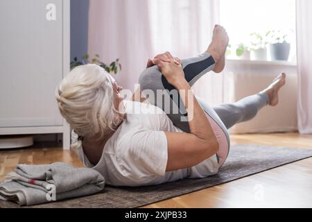 Ältere Frau, die zu Hause Pilates auf Matte macht Stockfoto
