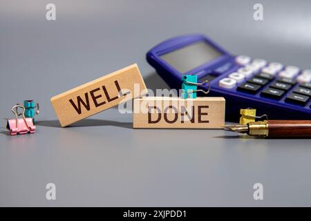 Gut gemacht Symbol. Holzblöcke mit Worten gut gemacht. Schöner grauer grüner Hintergrund mit saftiger Pflanze. Geschäft und gut durchführtes Konzept. Kopierbereich Stockfoto