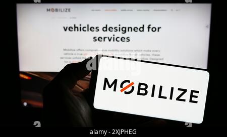 Stuttgart, Deutschland, 18.06.2023: Person, die ein Mobiltelefon mit dem Logo eines Automobilunternehmens für Mobilität hält, auf dem Bildschirm vor der Website des Unternehmens mobilisiert. Stockfoto
