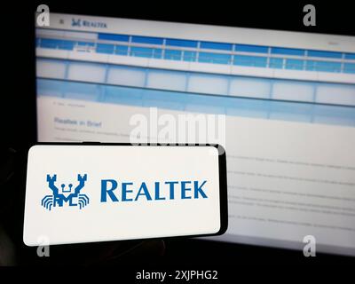 Stuttgart, 23.06.2023: Person, die ein Mobiltelefon mit dem Logo des taiwanesischen Unternehmens Realtek Semiconductor Corp. Auf dem Bildschirm vor der Webseite hält. Stockfoto