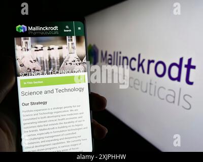 Stuttgart, 24.06.2023: Person, die ein Handy hält, mit Webseite der Firma Mallinckrodt Pharmaceuticals plc vor dem Logo auf dem Bildschirm. Fokus Stockfoto