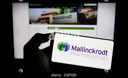 Stuttgart, 24.06.2023: Person, die ein Mobiltelefon mit dem Logo der Firma Mallinckrodt Pharmaceuticals plc auf dem Bildschirm vor dem Geschäft hält Stockfoto