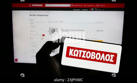 Stuttgart, 24.06.2023: Person, die ein Mobiltelefon mit dem Logo des griechischen Elektronikeinzelhandelsunternehmens Kotsovolos auf dem Bildschirm vor dem Geschäft hält Stockfoto