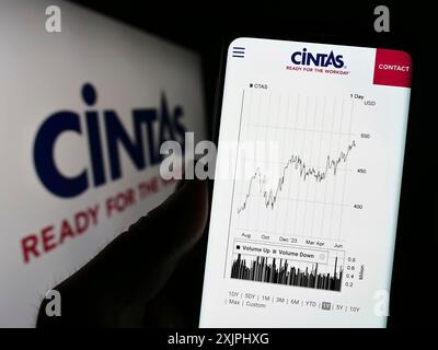 Stuttgart, Deutschland: 25.06.2023: Person, die ein Mobiltelefon hält, mit Webseite der US-amerikanischen Cintas Corporation vor dem Firmenlogo. Konzentrieren Sie sich auf Stockfoto