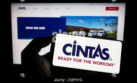 Stuttgart, Deutschland: 25.06.2023: Person, die ein Mobiltelefon mit dem Logo des amerikanischen Unternehmens Cintas Corporation auf dem Bildschirm vor der Webseite hält. Stockfoto