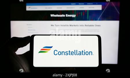 Stuttgart, 25.06.2023: Person, die ein Mobiltelefon mit dem Logo der US-amerikanischen Firma Constellation Energy Corporation auf dem Bildschirm vor dem Geschäft hält Stockfoto