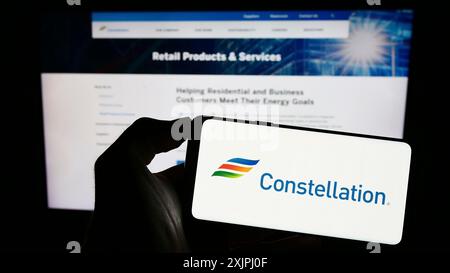 Stuttgart, 25.06.2023: Person, die ein Smartphone mit dem Logo des US-amerikanischen Unternehmens Constellation Energy Corporation auf dem Bildschirm vor der Website hält. Stockfoto