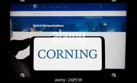 Stuttgart, 25.06.2023: Person, die ein Mobiltelefon mit dem Logo des US-amerikanischen Technologieunternehmens Corning Incorporated auf dem Bildschirm vor dem Unternehmen hält Stockfoto