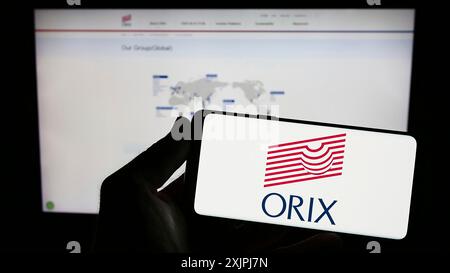 Stuttgart, Deutschland, 07.01.2023: Person, die ein Smartphone mit dem Logo des japanischen Finanzunternehmens ORIX Corporation auf dem Bildschirm vor der Website hält. Stockfoto