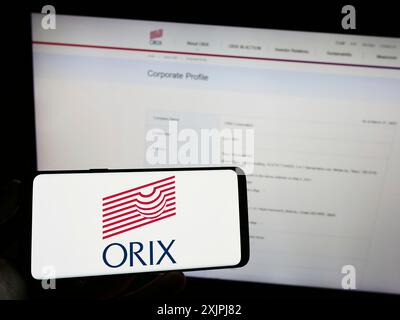 Stuttgart, Deutschland, 07.01.2023: Person, die ein Mobiltelefon mit dem Logo des japanischen Finanzunternehmens ORIX Corporation vor dem Geschäft auf dem Bildschirm hält Stockfoto