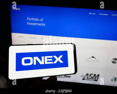 Stuttgart, Deutschland, 07.01.2023: Person, die ein Mobiltelefon mit dem Logo der kanadischen Investmentgesellschaft Onex Corporation auf dem Bildschirm vor der Webseite hält. Stockfoto