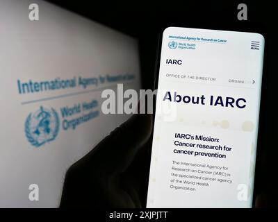 Stuttgart, Deutschland, 07.04.2023: Person, die ein Handy hält, mit Webseite der Internationalen Krebsforschungsagentur (IARC) auf dem Bildschirm mit Logo. Stockfoto