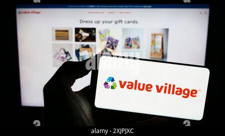 Stuttgart, Deutschland, 07.06.2023: Person mit Mobiltelefon mit Logo des Einzelhandelsunternehmens Value Village (Savers) auf dem Bildschirm vor der Unternehmenswebseite. Stockfoto