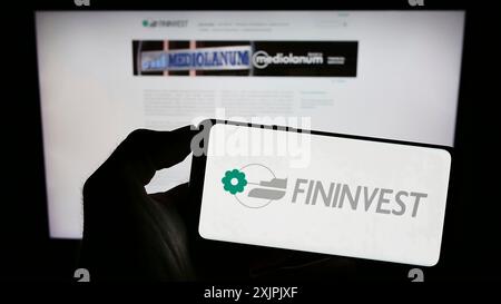 Stuttgart, Deutschland, 07.06.2023: Person mit Mobiltelefon mit Logo der italienischen Holdinggesellschaft Fininvest S.p.A. auf dem Bildschirm vor dem Geschäft Stockfoto