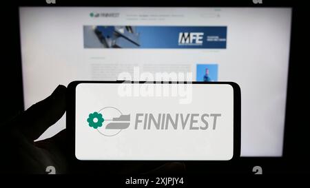 Stuttgart, Deutschland, 07.06.2023: Person, die ein Smartphone mit dem Logo der italienischen Holdinggesellschaft Fininvest S.p.A. auf dem Bildschirm vor der Website hält. Fokus Stockfoto
