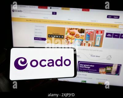 Stuttgart, Deutschland, 07.08.2023: Person, die ein Mobiltelefon mit dem Logo des britischen E-Commerce-Unternehmens Ocado Retail Limited auf dem Bildschirm vor dem Internet hält Stockfoto