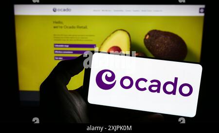 Stuttgart, Deutschland, 07.08.2023: Person mit Mobiltelefon mit Logo des britischen E-Commerce-Unternehmens Ocado Retail Limited auf dem Bildschirm vor der Webseite. Stockfoto