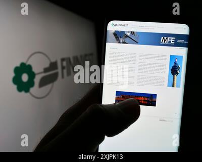 Stuttgart, Deutschland, 07.06.2023: Person mit Smartphone und Website der italienischen Holdinggesellschaft Fininvest S.p.A. auf dem Bildschirm vor dem Logo. Fokus Stockfoto