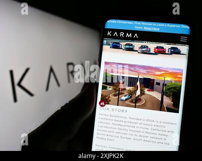 Stuttgart, Deutschland, 07.08.2023: Person, die ein Smartphone hält, mit Webseite des Elektrofahrzeugunternehmens Karma Automotive LLC auf dem Bildschirm mit Logo. Fokus Stockfoto
