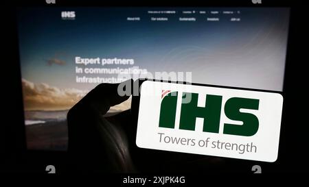 Stuttgart, Deutschland, 07-08-2023: Person, die ein Smartphone mit dem Logo des Telekommunikationsunternehmens IHS Holding Limited auf dem Bildschirm vor der Website hält. Stockfoto