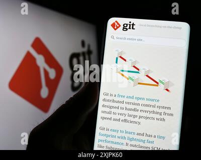 Stuttgart, Deutschland, 07.09.2023: Person, die ein Mobiltelefon hält, mit Webseite des verteilten Versionskontrollsystems Git auf dem Bildschirm vor dem Logo. Konzentrieren Sie sich auf Stockfoto