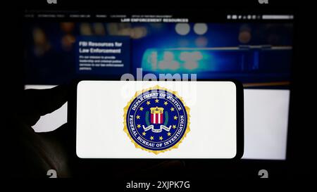 Stuttgart, Deutschland, 07-09-2023: Person, die ein Mobiltelefon mit dem Siegel des amerikanischen Bundesforschungsbüros (FBI) auf dem Bildschirm vor der Webseite hält. Stockfoto