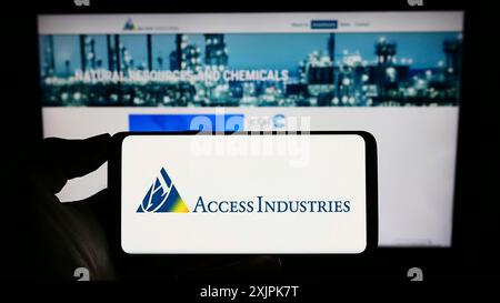 Stuttgart, Deutschland, 07.08.2023: Person, die ein Mobiltelefon mit dem Logo der US-Holding Access Industries Inc. Auf dem Bildschirm vor dem Geschäft hält Stockfoto