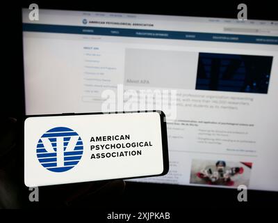 Stuttgart, Deutschland, 07.11.2023: Person, die ein Smartphone mit dem Logo der American Psychological Association (APA) auf dem Bildschirm vor der Website hält. Fokus Stockfoto