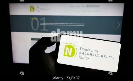 Stuttgart, Deutschland, 07.11.2023: Person mit Mobiltelefon mit Logo des Deutschen Nachhaltigkeitskodex (DNK) auf dem Bildschirm vor der Webseite. Konzentrieren Sie sich auf Stockfoto