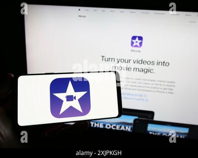 Stuttgart, Deutschland, 07.12.2023: Person, die ein Smartphone mit dem Logo der Videobearbeitungssoftware iMovie (Apple Inc.) auf dem Bildschirm vor der Website hält. Stockfoto